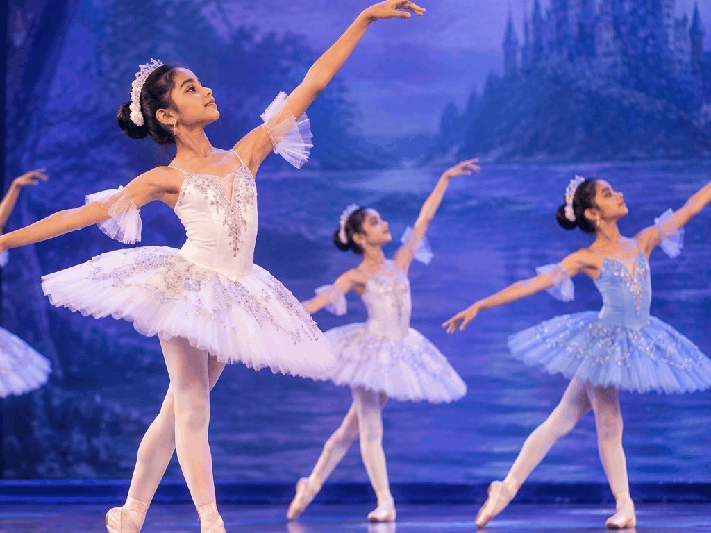 Young ballerinas in pastel tutus dancing on a stage