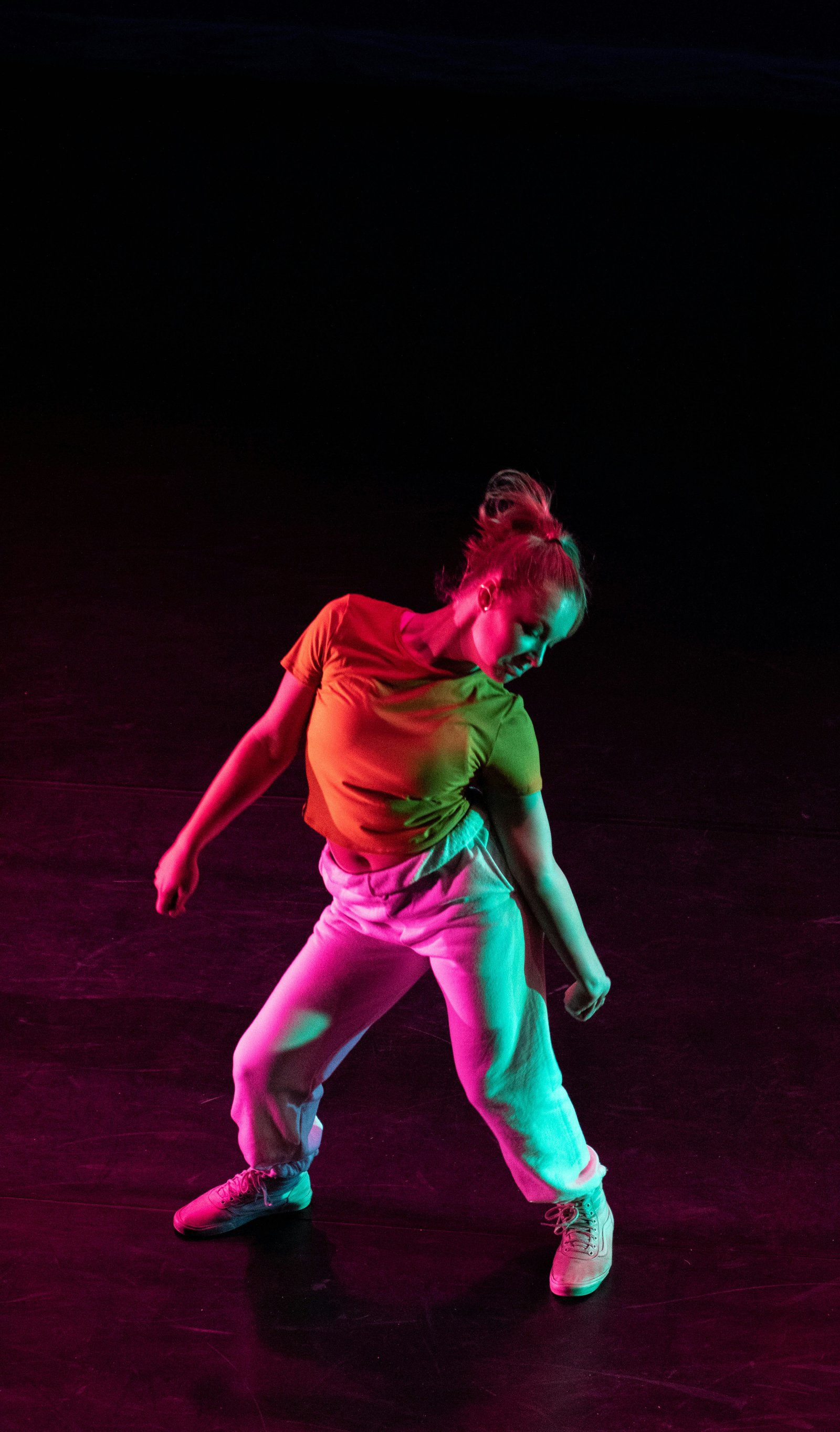 Dancer in a contemporary pose under pink and teal light